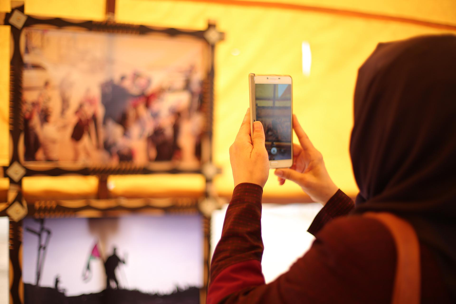 Mujer con hiyab tomando una foto con un teléfono móvil