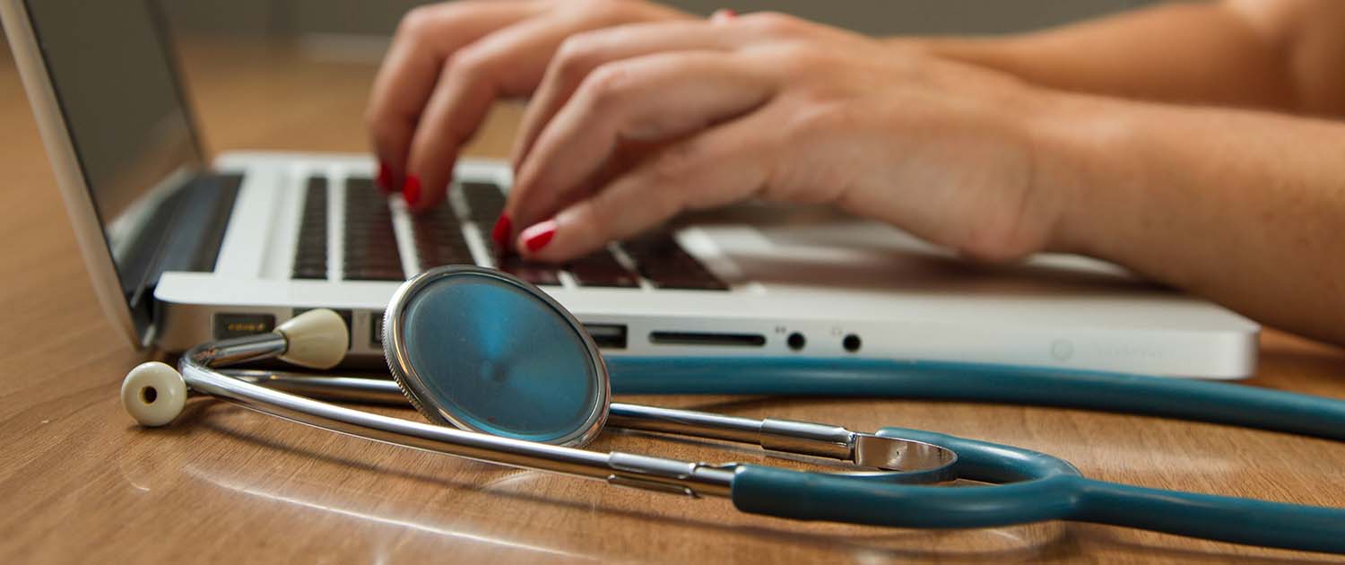 Stethoscope next to a laptop.